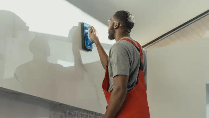Cleaner in overalls scrubbing a wall