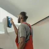 Cleaner in overalls scrubbing a wall