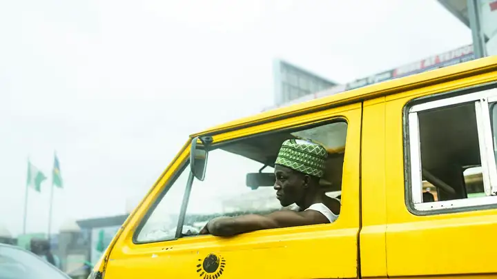 Driver at the wheel of a yellow bus in Lagos traffic