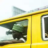 Driver at the wheel of a yellow bus in Lagos traffic