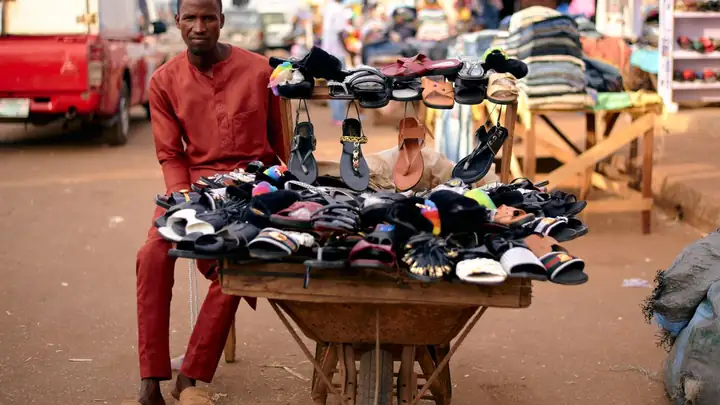 Trader selling sandals from a barrow at a market in Jos