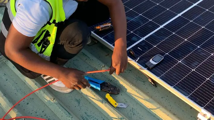 Technician wiring solar panels on a roof