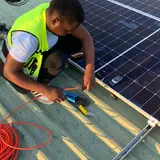 Technician wiring solar panels on a roof