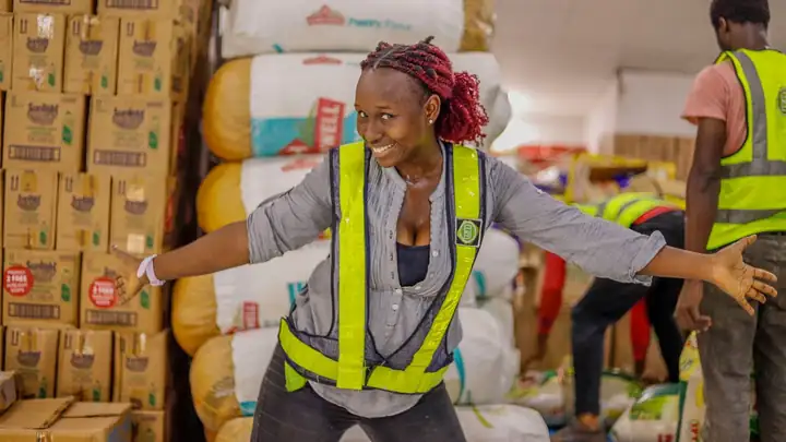 Warehouse worker in a hi-vis vest among stacked cartons