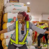 Warehouse worker in a hi-vis vest among stacked cartons